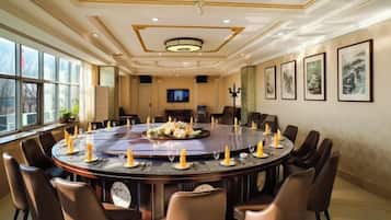 Un salón de conferencias con una mesa redonda, sillas y una pantalla de televisión.