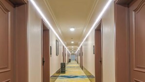 A hotel hallway with a carpeted floor, doors on both sides, and overhead lighting. - Donggang Yuyun Hotel (Donggang)