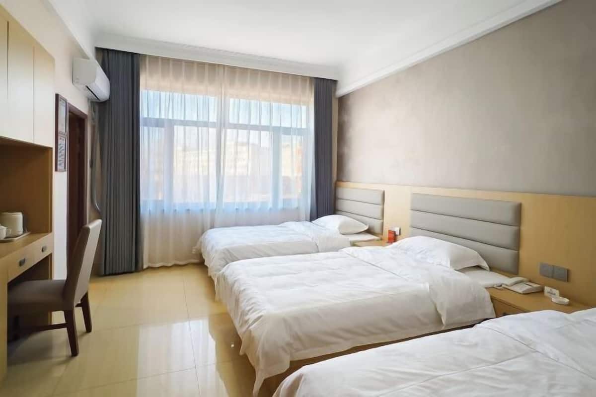 A hotel room with three beds, a desk, and a chair.