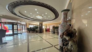 A spacious lobby with a polished tile floor, a large decorative vase, and a circular ceiling design. - Donggang Yuyun Hotel (Donggang)