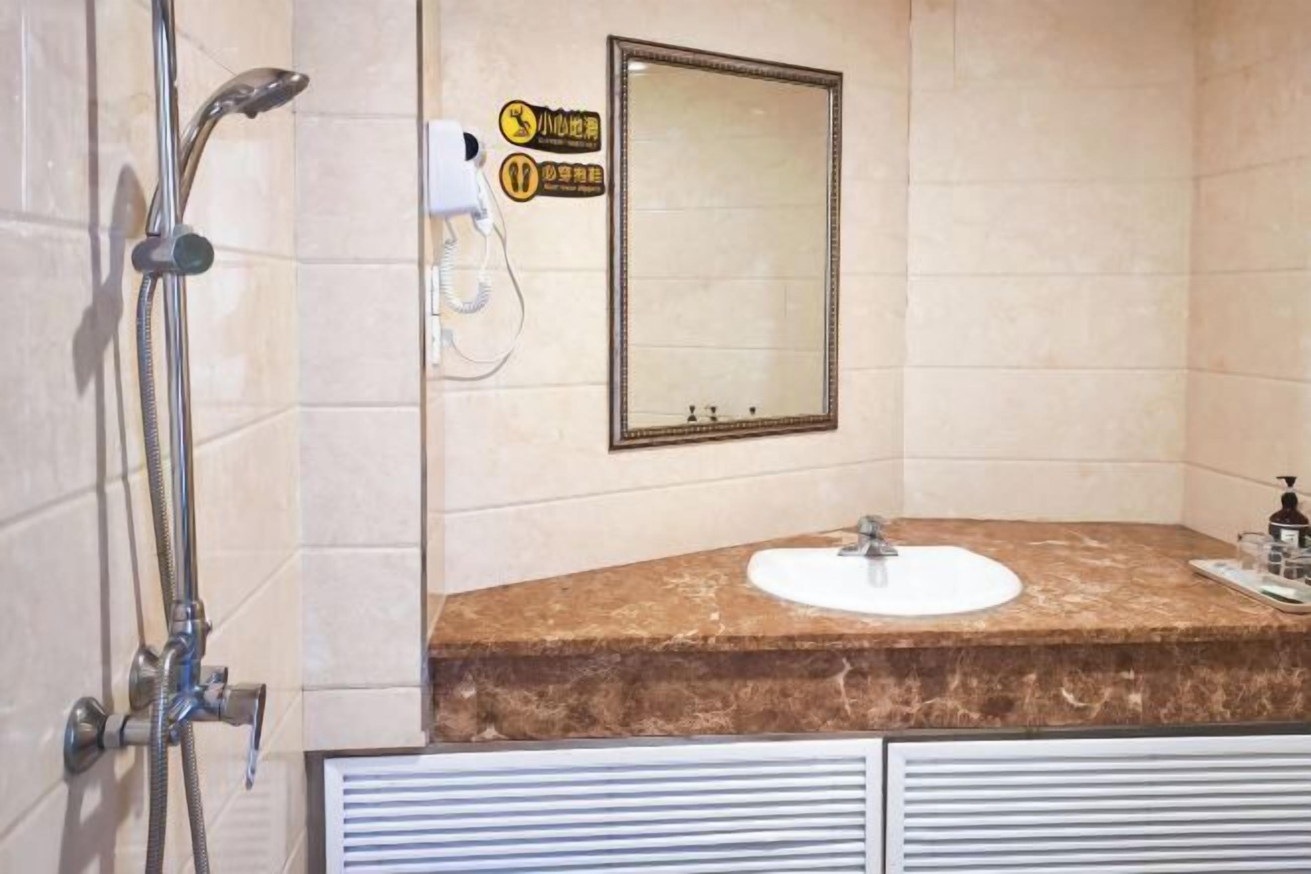 A bathroom with a marble sink, a mirror, and a shower.
