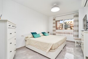 Une chambre à coucher avec un lit, une commode, un bureau et une fenêtre avec des rideaux.