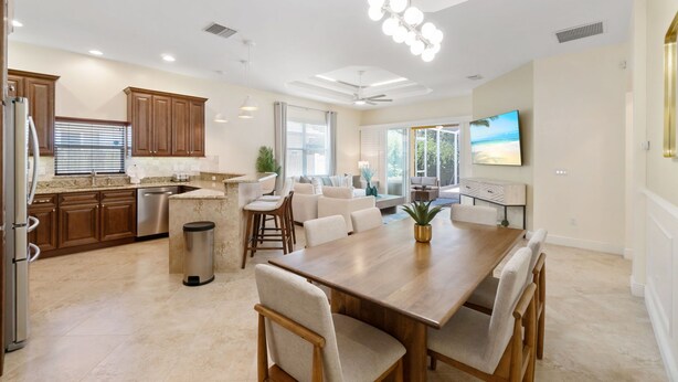 Una cocina amplia con armarios de madera, un comedor con mesa y sillas de madera, y una sala de estar con sofá y televisor.