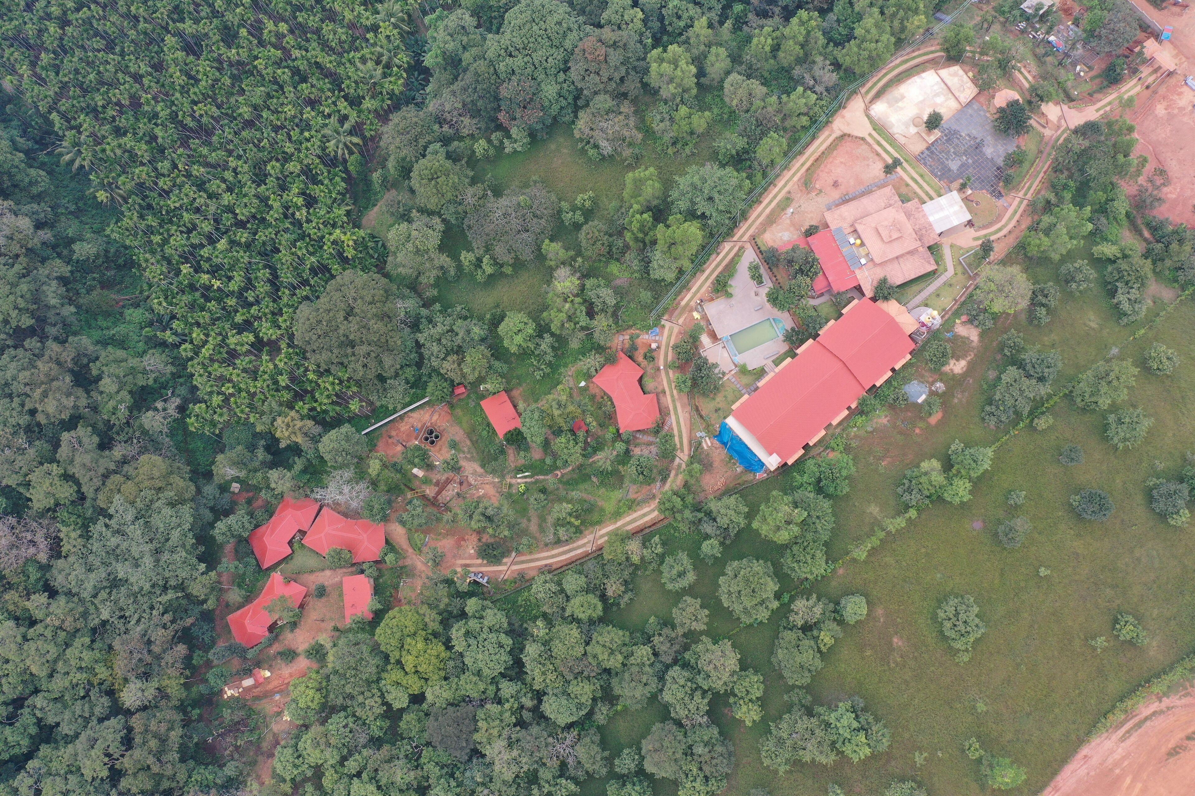 Vista aérea de una propiedad con varias construcciones, rodeada de un denso bosque.
