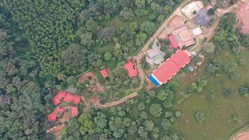 Vista aérea de una propiedad con varias construcciones, rodeada de un denso bosque.