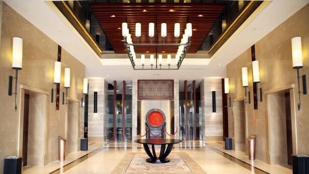 A modern lobby with a central round table, a chandelier, and a red circular artwork on the wall. - Ji'an Hotel (Ji'an)