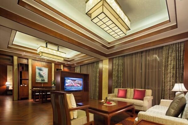 A hotel room with a wooden floor, a television, a sofa, a dining table, and a ceiling with recessed lighting. - Ji'an Hotel (Ji'an)