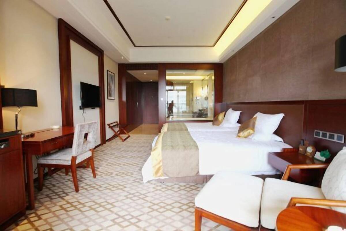 Ein Hotelzimmer mit Schreibtisch, zwei Betten, einer Couch und einem Fernseher.