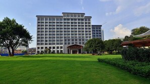 A large hotel with a central entrance, surrounded by a well-maintained lawn and trees. - Ji'an Hotel (Ji'an)
