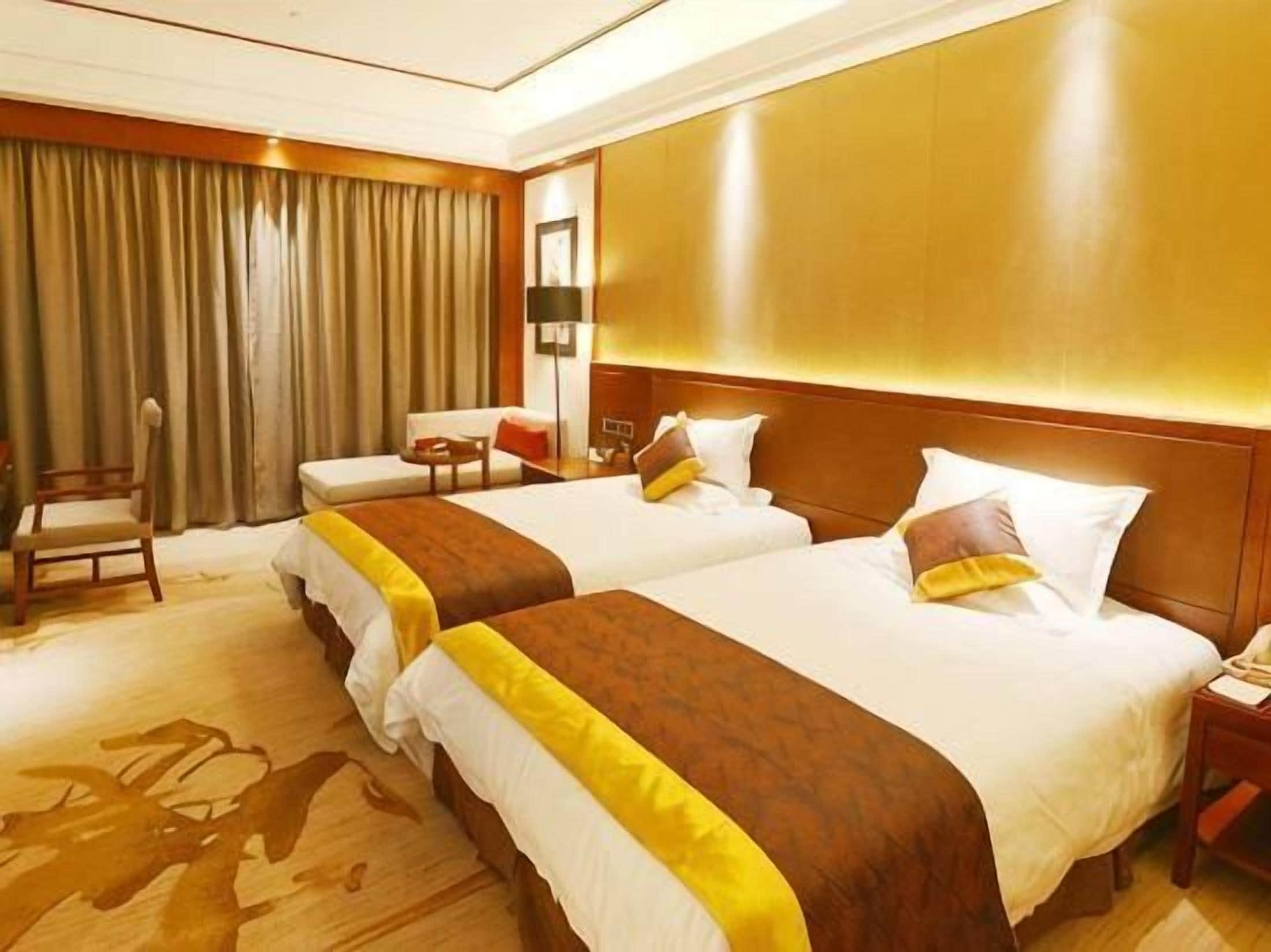 A hotel room with two beds, a desk, a chair, and a large window with curtains.
