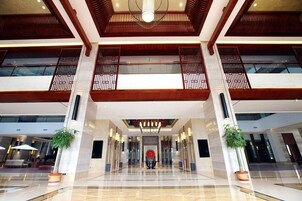 A spacious lobby with a high ceiling, modern lighting fixtures, and a central decorative element.