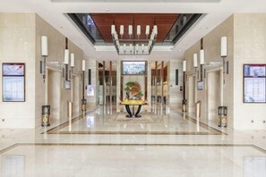 A spacious lobby with a central reception desk, a ceiling with a wooden panel design, and a polished floor. - Ji'an Hotel (Ji'an)