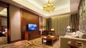A hotel room with a television, a wooden entertainment unit, a sofa, a coffee table, and a chandelier. - Ji'an Hotel (Ji'an)
