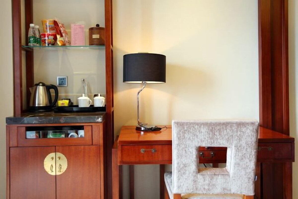 A compact room with a wooden cabinet, a small desk with a lamp, and a chair.