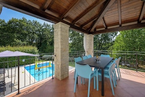 Relax by the pool surrounded by a patio with a stone pillar backdrop and a table for al fresco dining.