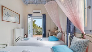 A room with two beds, a framed picture, an air conditioning unit, and a view of the outdoors. - Villa Simeoni Country House with Lake View, Wi-Fi, and Air Conditioning (Lefkada Town)