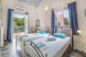 Una camera da letto con due letti, un comodino, tende a una finestra e un condizionatore d'aria.