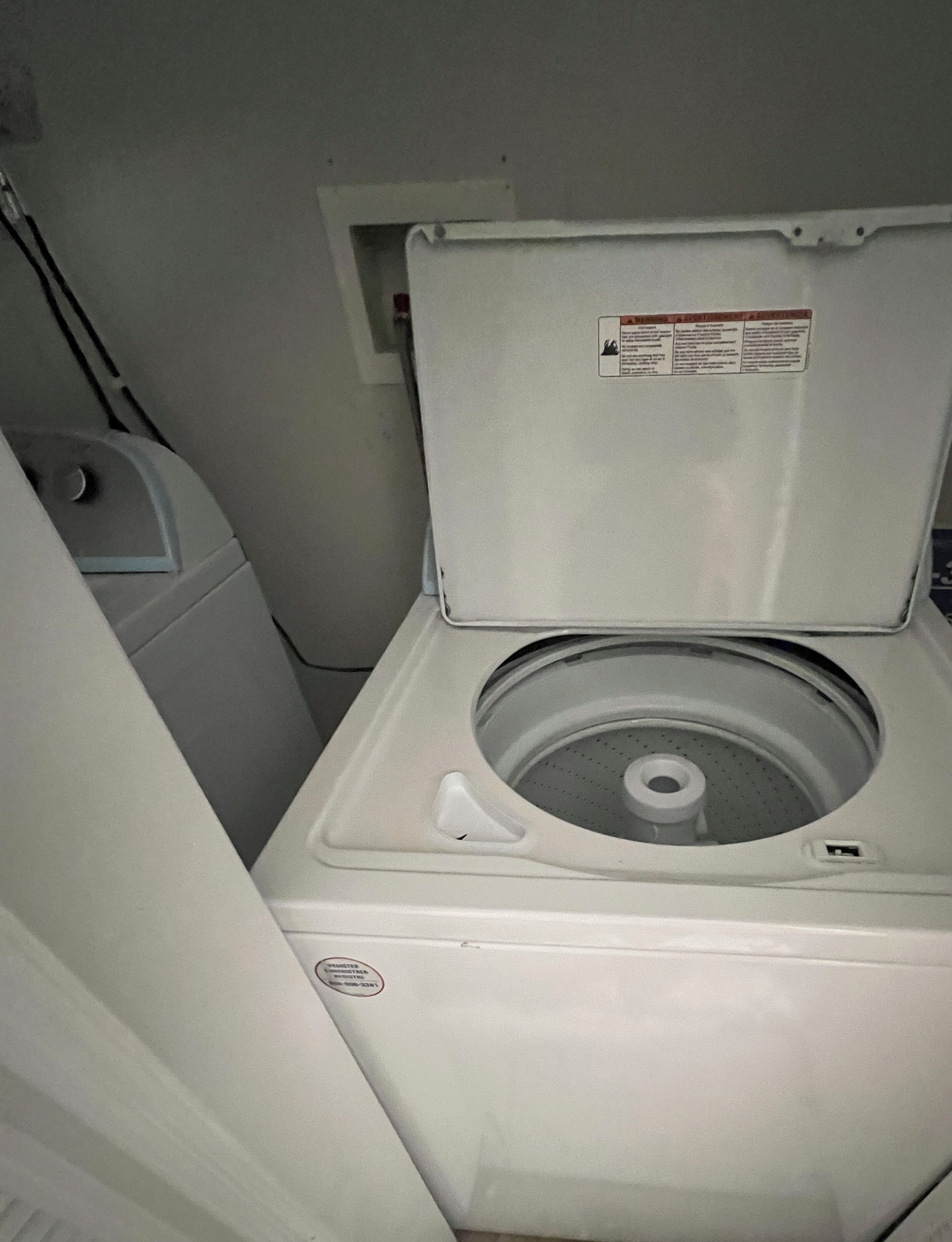 Eine kompakte, weiße, an der Wand befestigte Waschmaschine in einem kleinen Raum.