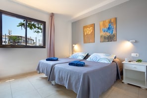 A hotel room with two beds, a window with a view, and two paintings on the wall. - Vacation Home 'Oasis Royal E204' with Shared Pool, Shared Terrace and Wi-Fi (Corralejo)