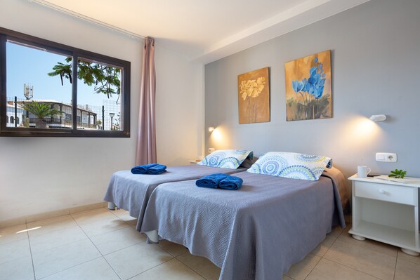 Habitación de hotel con dos camas, una ventana con vistas y dos cuadros en la pared.