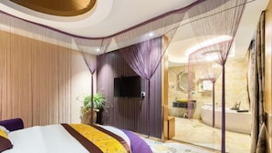 A modern hotel room with a large bed, a TV, a bathroom with a bathtub, and a decorative canopy. - Geyue Zhenpin Hotel (Hangzhou)