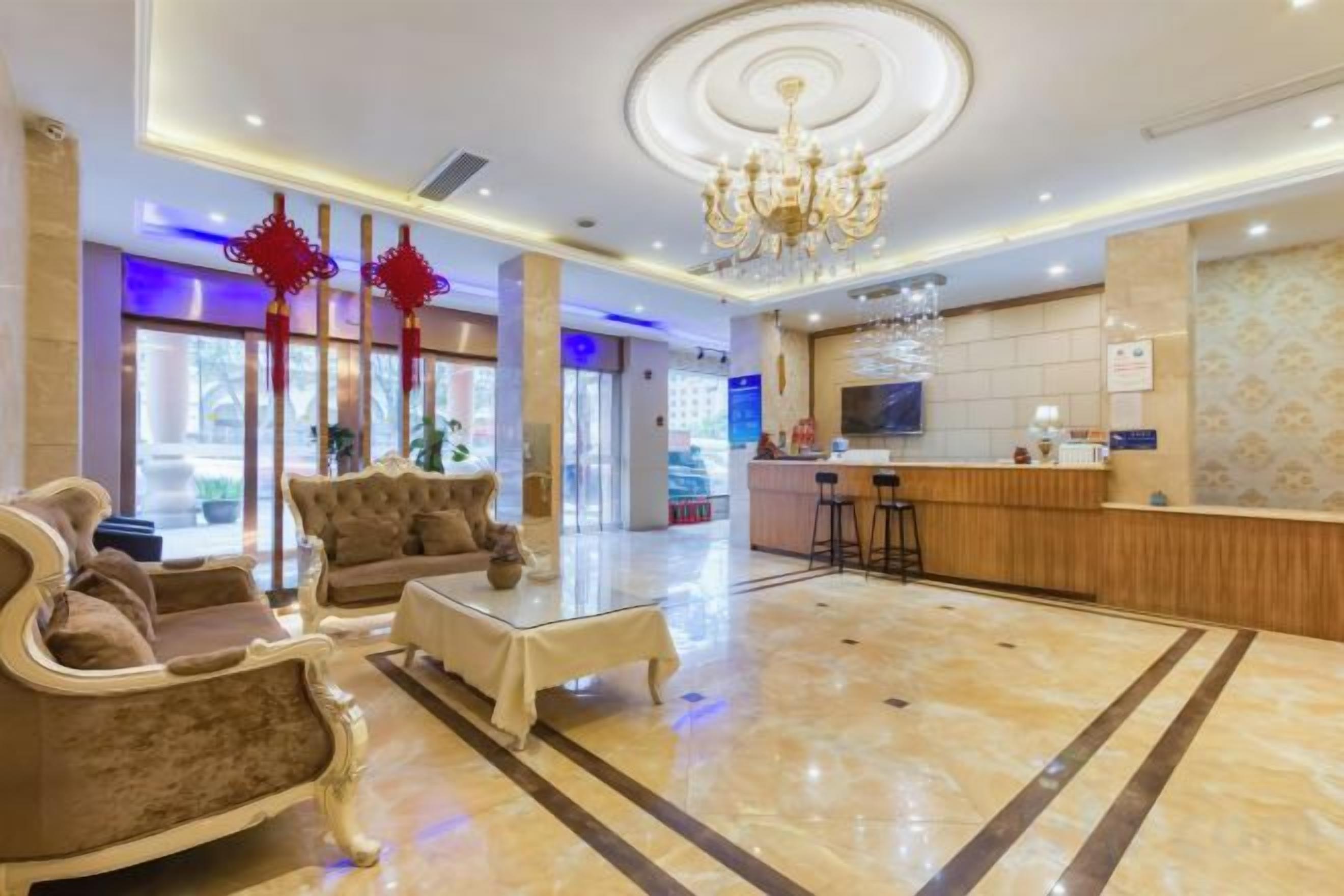 Um saguão de hotel com balcão de recepção, área de estar e um candelabro.