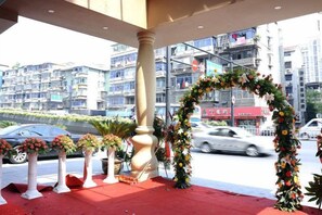 Un espace extérieur agrémenté d’un tapis rouge, de colonnes blanches et d’une arche décorée de fleurs.