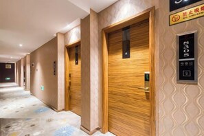 Een hotelgang met houten deuren, een kamerbreed tapijt met dessin en een bordje dat een rookvrij gebied aangeeft.