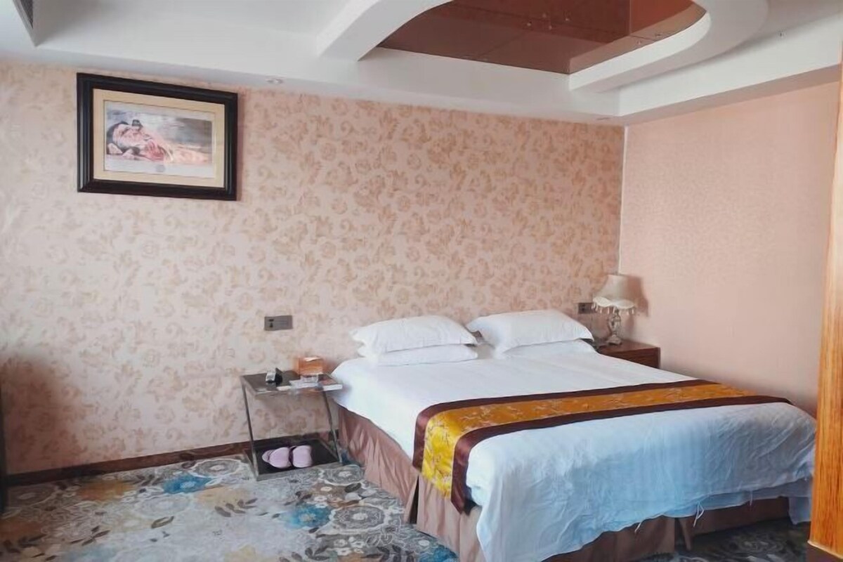 A bedroom with a bed, a nightstand, a lamp, and a patterned rug.