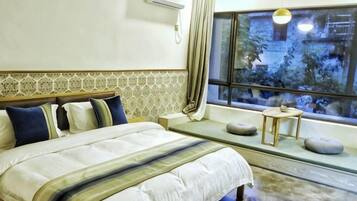 Habitación de hotel con cama, una mesita, ventana con vistas y aire acondicionado de pared.