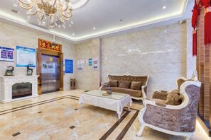 A hotel lobby with a marble floor, a fireplace, a sofa, a coffee table, and a chandelier. - Geyue Zhenpin Hotel (Hangzhou)
