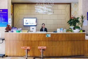 Una reception con uno schermo televisivo, una pianta e un cartello che indica le tariffe delle camere.