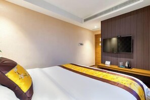 A hotel room with a bed, a TV, a wooden panel wall, and a small table with a kettle. - Geyue Zhenpin Hotel (Hangzhou)
