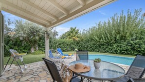 Ein überdachter Patio mit Poolbillard, Stühlen und einem Babygehwagen.