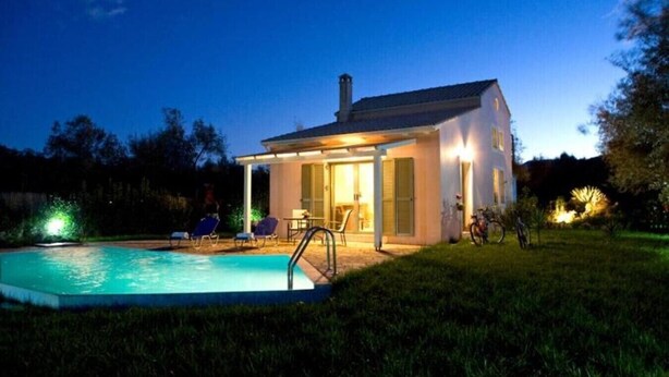 Ein modernes Haus mit Schwimmbad, Sitzgelegenheiten im Freien und einem Fahrrad.