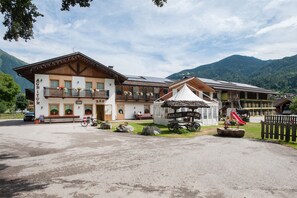 A traditional mountain lodge with a bar, outdoor seating, and a small play area.