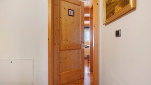 A wooden door with a number, a framed picture on the wall, and a light switch.