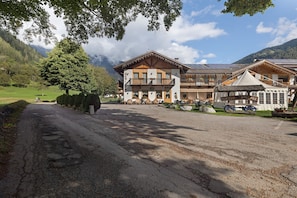 Un albergue de montaña con fachada de madera, un balcón y vistas del paisaje circundante.