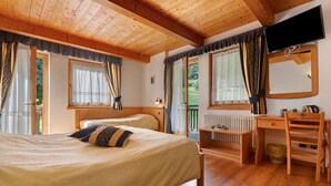 A wooden-paneled room with two beds, a desk, and a TV.