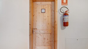 A wooden door with a fire extinguisher mounted on the wall beside it.