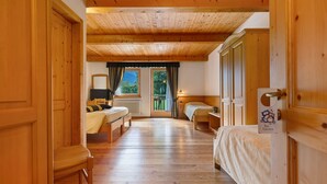A wooden-floored room with two beds, a window with curtains, and a door with a sign.