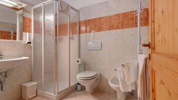 Ein Badezimmer mit Dusche, Toilette, Bidet und Waschbecken.
