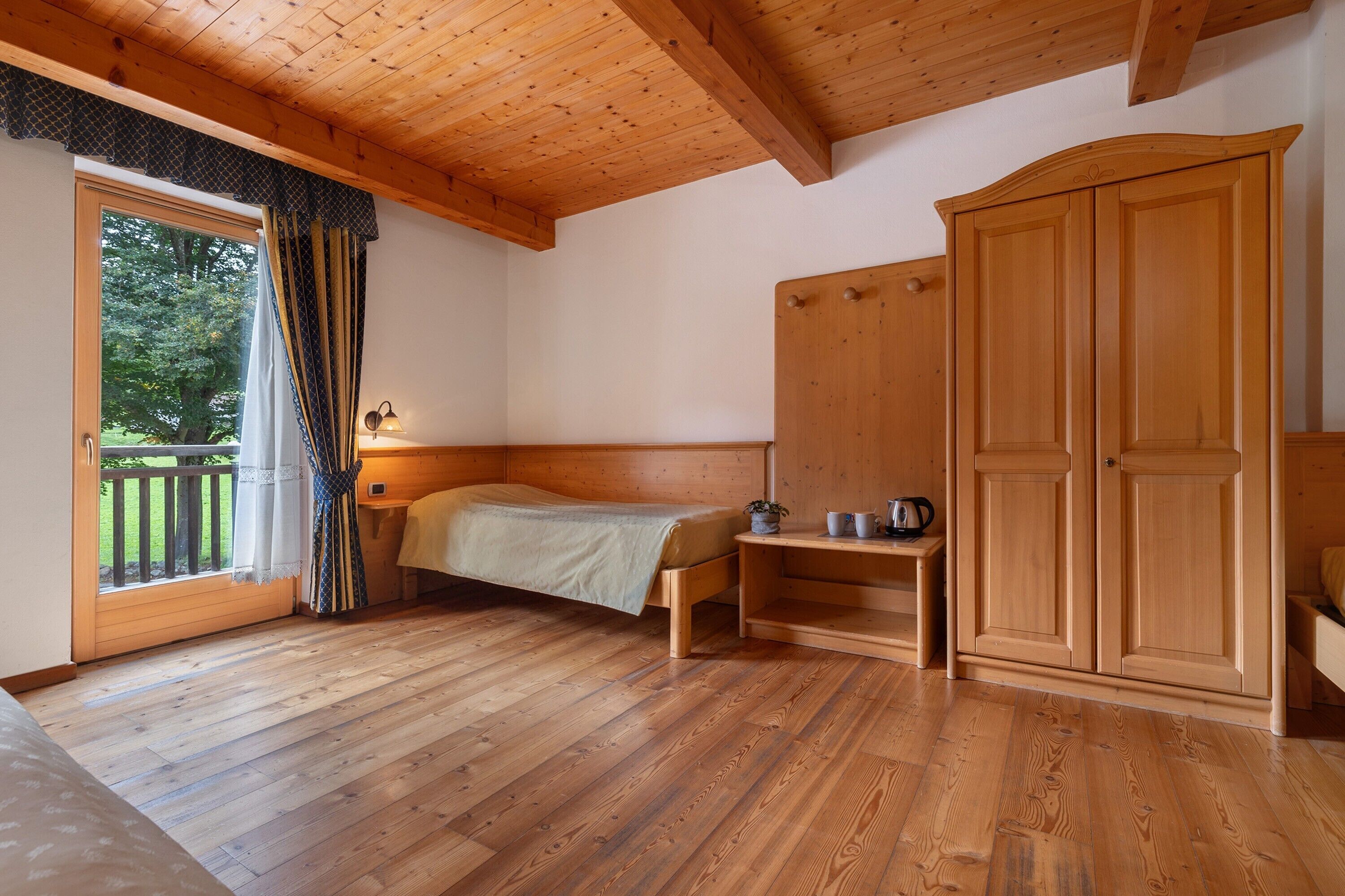 Una habitación con paneles de madera, una cama, un armario y una pequeña mesa.