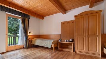 Una habitación con paneles de madera, una cama, un armario y una pequeña mesa.