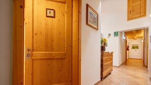 Una puerta de madera, un mostrador de recepción, un pasillo con piso de baldosas y un cuadro enmarcado en la pared.