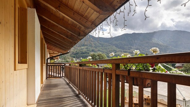 Una terraza de madera con barandilla, con vistas a un paisaje montañoso.