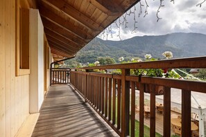 Une terrasse en bois dotée d’une rambarde, offrant une vue sur un paysage montagneux.