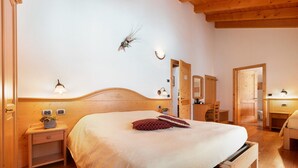 A wooden-framed bedroom with a bed, bedside tables, a nightstand, a mirror, and a wall-mounted light fixture. - Room 'Camera Tripla N 5' with Mountain View, Shared Garden and Wi-Fi (Caderzone Terme)