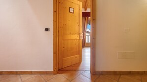 A wooden door with a number plate, a tiled floor, and a light switch on the wall. - Room 'Camera Tripla N 5' with Mountain View, Shared Garden and Wi-Fi (Caderzone Terme)