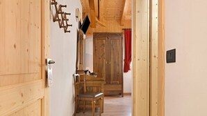 A wooden interior hallway with a dining table and chairs, a wooden door, and a wall-mounted light switch. - Room 'Camera Doppia Comunicante Nonni' with Mountain View, Shared Garden and Wi-Fi (Caderzone Terme)